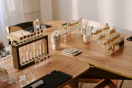 Wide angle shot of cosmetic lab workspace displaying test tubes, dropper bottles, scale, formulation tools for skincare product and perfume development and beauty brand content marketing