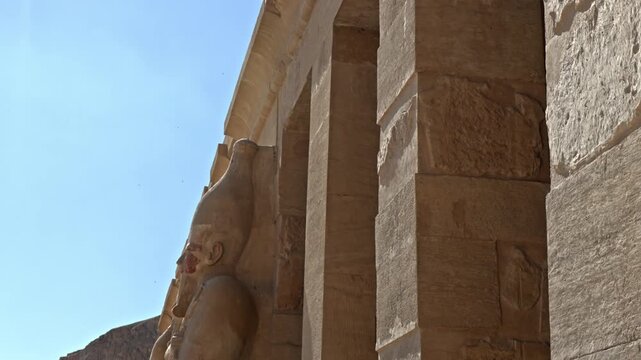 A low-angle, profile shot looking down the upper terrace colonnade of the Mortuary Temple of Hatshepsut at Deir el-Bahari in Luxor, Egypt.