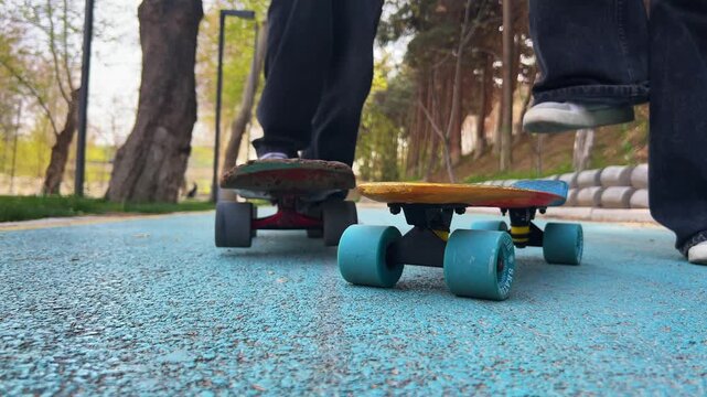 Longboards on blue pavement with skaters walking in park