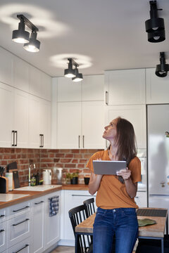 Woman controlling lights through digital tablet at home