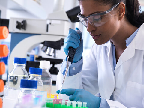 Genetic research, female scientist pipetting DNA or chemical sample into a eppendorf vial, analysis in the laboratory