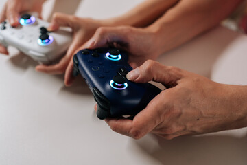 Close-up cropped shot of young adult couple holding wireless game controllers, playing video games together, sharing leisure time and entertainment at home, enjoying fun competitive hobby. © dikushin