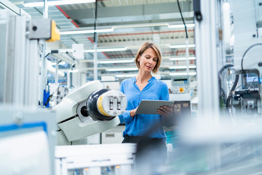 Businesswoman with tablet at assembly robot in a factory