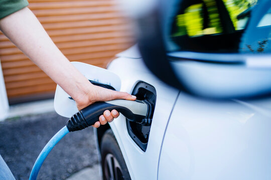 Hand of woman charging electric car