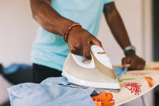 Young man ironing shirt at home