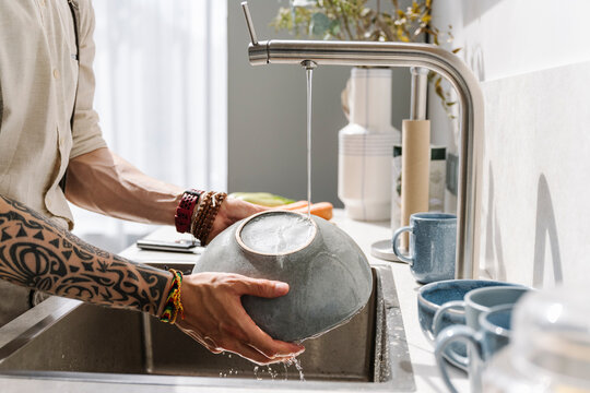 Man washing bowl in sink at home