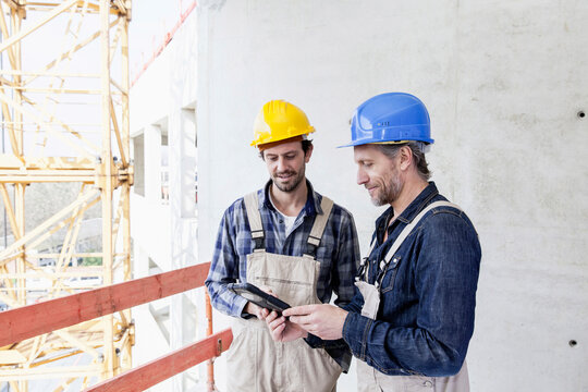 Two construction workers on construction site looking at digital tablet