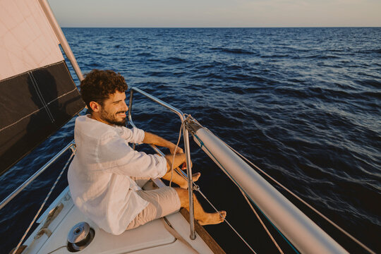 Smiling sailor relaxing on a sailboat deck during summer vacation