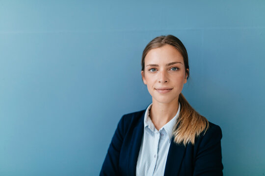 Portrait of a young businesswoman against blue background