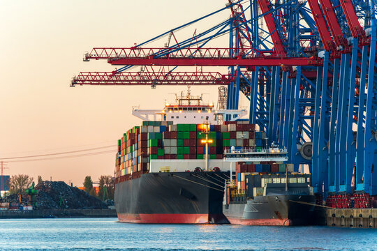 Container ship loading cargo at Hamburg harbor during dusk
