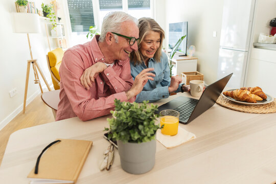 Smiling couple enjoying a morning video call on laptop at home