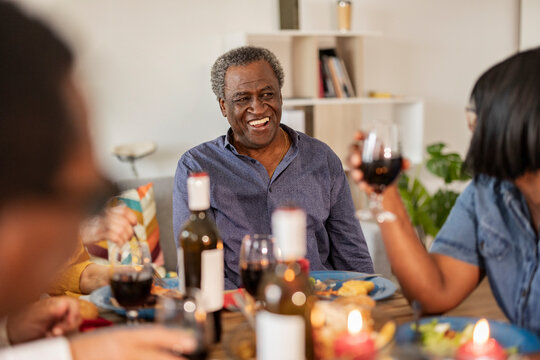 Happy senior man talking to friend holding wineglass at home