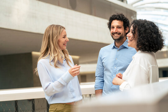 Happy business colleagues discussing in office corridor