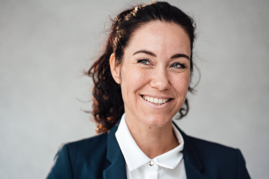 Smiling businesswoman in front of gray wall