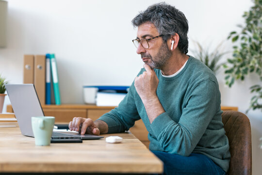 Freelancer concentrating on laptop at home office desk