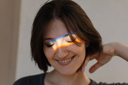 Smiling young woman with multi-colored light on face