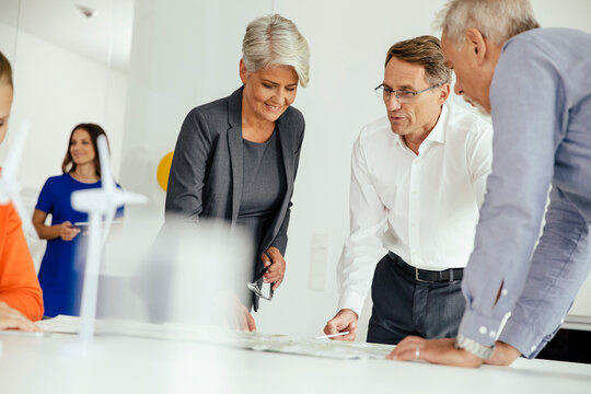 Business people discussing plan with wind turbine model on conference table