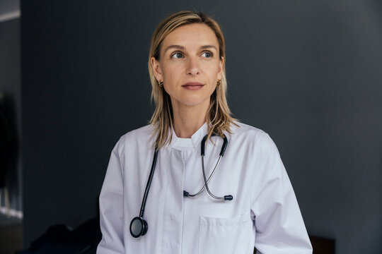 Portrait of doctor against grey background looking at distance