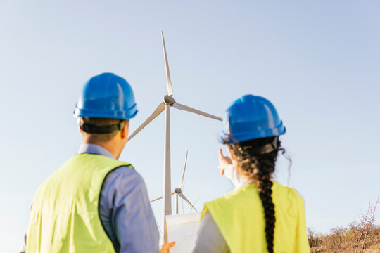 Engineer with colleague gesturing and discussing over wind turbines