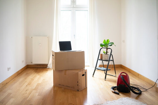 Piled cardboard boxes and laptop in an empty room