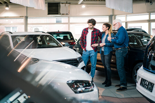 Car dealer showing cars to couple in showroom