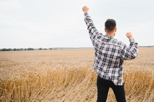 Farmer celebrating with raised arms in wheat field