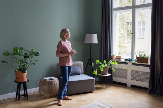 Mature woman at home looking out of window