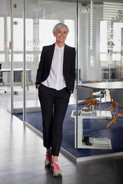 Portrait of fashionable senior businesswoman wearing pantsuit and sneakers in office