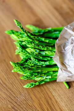 Fresh green asparagus in a paper bag on a wooden table