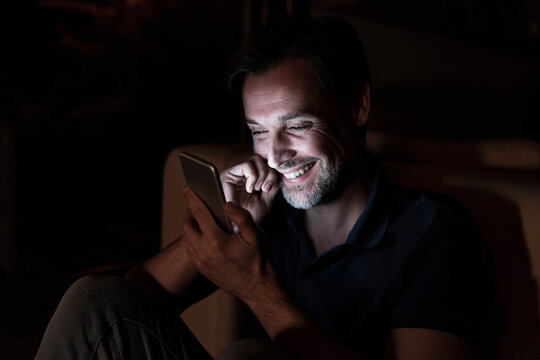 Portrait of happy mature man using cell phone at home