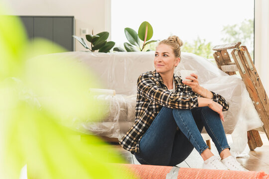 Woman sitting on the floor in new home having a coffee break
