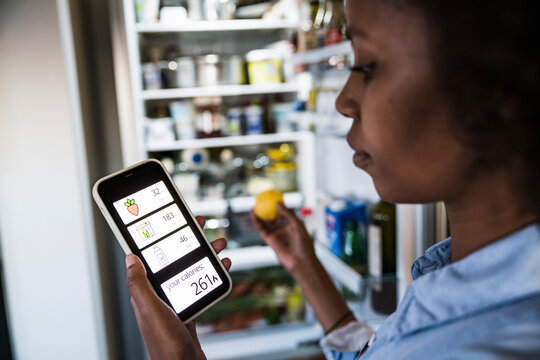 Woman tracking diet calories on a smartphone app in the kitchen