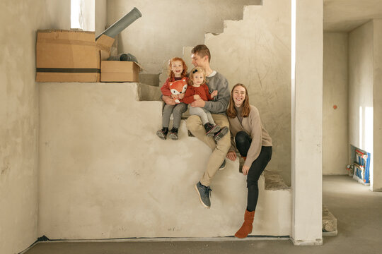 Happy family sitting on staircase at incomplete home