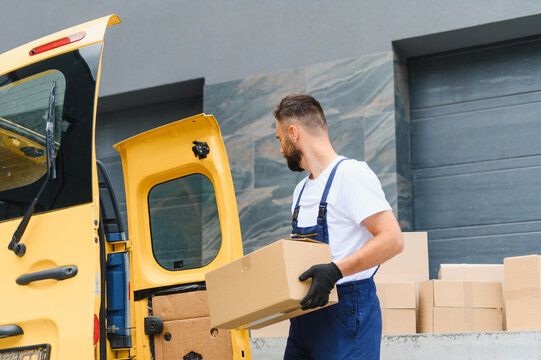 Courier loading cardboard boxes into delivery van