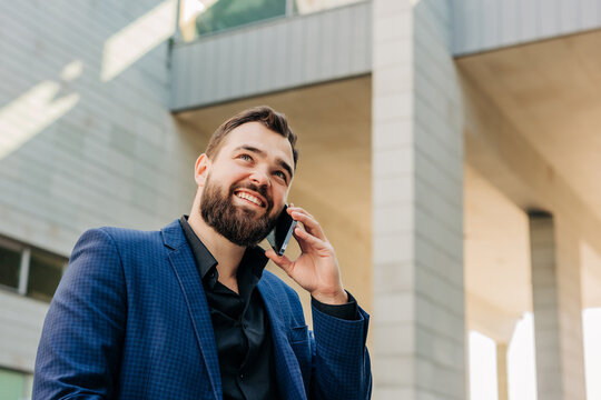 Smiling businessman in suit talking on smartphone outdoors