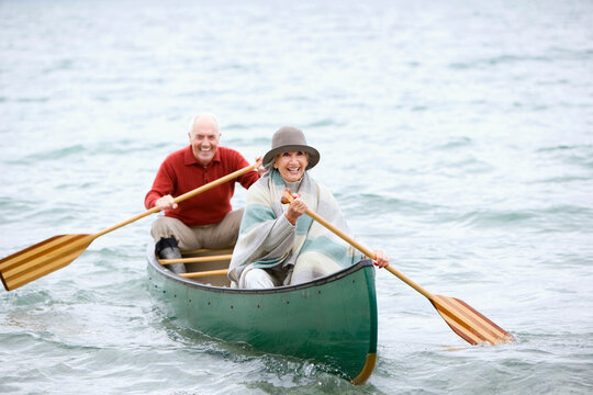 Smiling couple paddling a green canoe on Walchensee lake