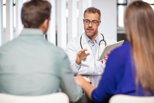 Doctor talking to couple in medical practice