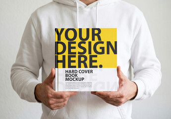 Square Hardcover Book Mockup Holding With Both Hands By Man in white hoodey
