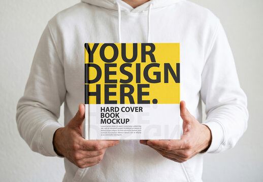 Square Hardcover Book Mockup Holding With Both Hands By Man in white hoodey