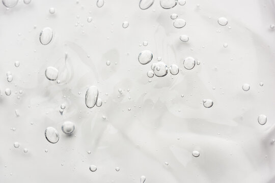 Transparent cosmetic gel or face serum product with texture and bubbles.