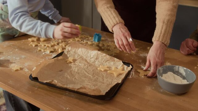 Cropped shot of senior and child placing star-shaped dough cookies onto baking sheet with parchment paper. Footage ideal for family lifestyle commercials or holiday baking promotions