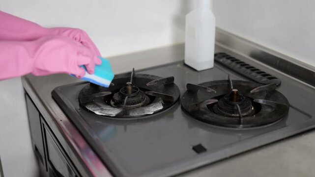 ガスコンロの油汚れを掃除する女性の手元のクローズアップ