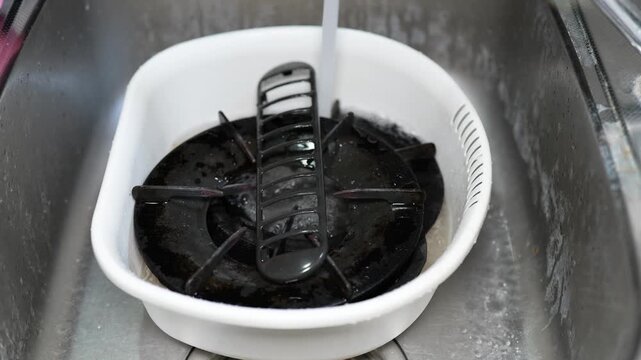 油で汚れたガスコンロの部品を取り外して水に浸す