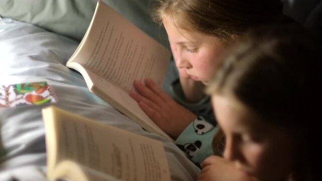 Twin sisters reading bedtime stories together before going to bed at night