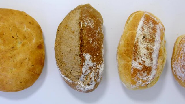 Bread from different types of flour of cereal seeds. Baking in straw baskets on a large wooden table. Rustic style. different types of bread on a white table round long black white