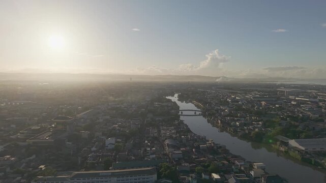 Drone footage moving left above Pasig River and Metro Manila during sunrise, revealing glowing skies, riverside communities, and expansive city views.