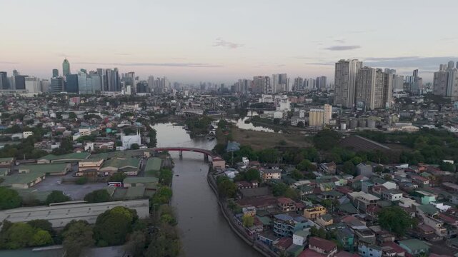 Drone footage moving backward above Pasig River with bridges, riverside communities, and the skyline of Metro Manila during early morning.