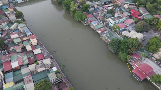 Drone footage moving forward above Pasig River, revealing riverside homes, urban neighborhoods, and tranquil waterways in Metro Manila, Philippines.