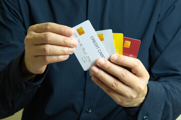 Close up of hand human holding multiple color credit cards, choosing a red card for payment,...