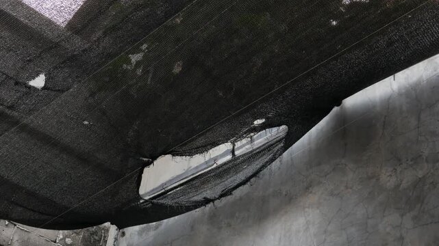 Close-Up of Torn Black Shade Cloth Roof Covering Outdoors